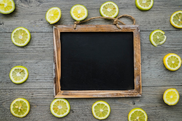 Wooden surface with lemon slices and blank slate