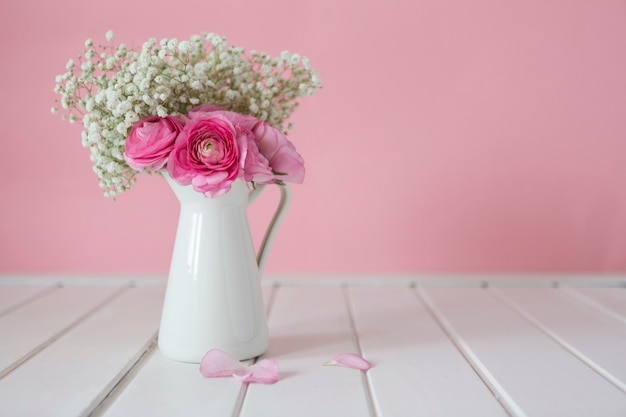 Wooden surface with petals and porcelain vase