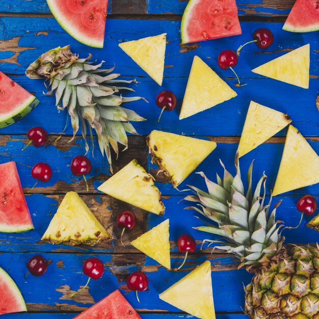 Wooden surface with pineapples, watermelons and cherries