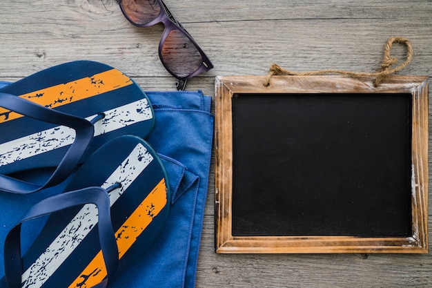 Free photo wooden surface with slate, flip flops and sunglasses