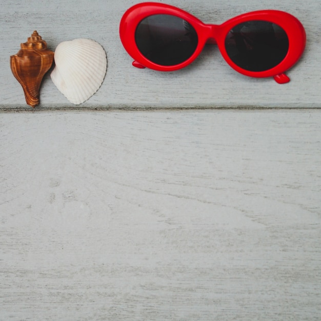 Foto gratuita superficie in legno con occhiali da sole e conchiglie