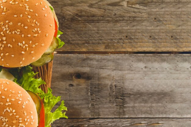 Wooden surface with tasty burgers and blank space