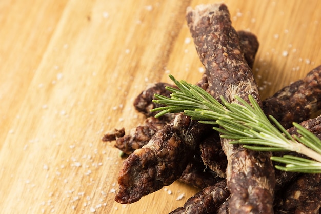 Wooden surface with traditional South African droewors with a rosemary seasoning on it