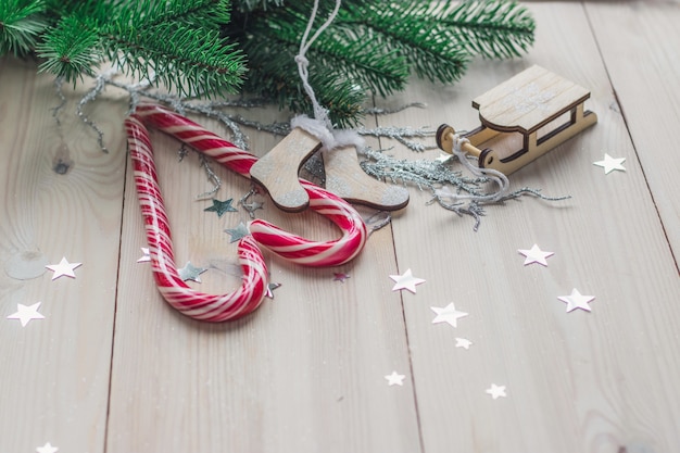 Free photo wooden table covered in candy canes and christmas decorations under the lights