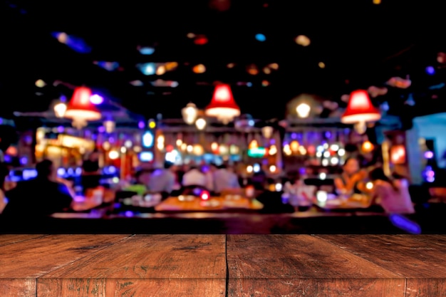 Wooden table in front of abstract blurred background of resturant lights