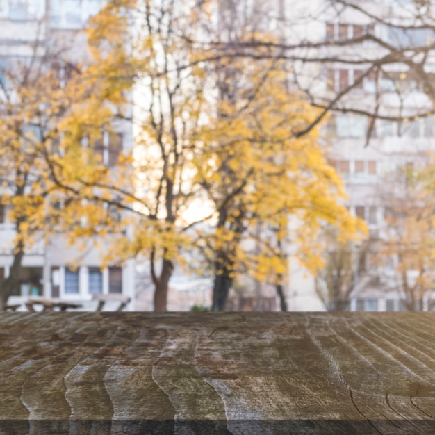 Wooden table in front of autumn trees and buildings