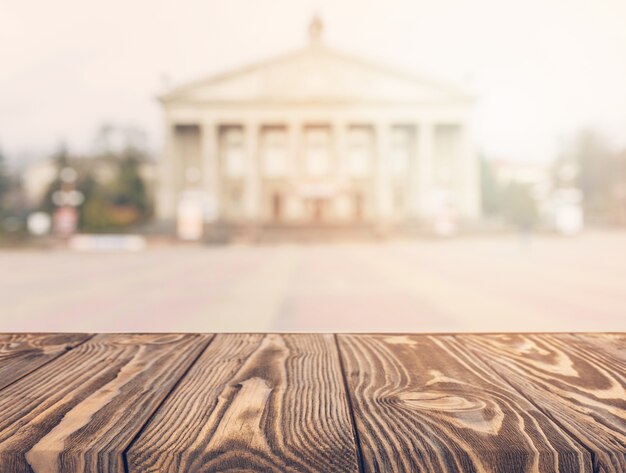 Wooden table in front of blurred facade of a classical public building