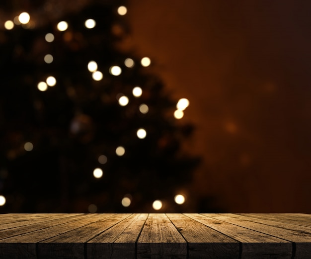 Defocussed 크리스마스 트리를 바라 보는 나무 테이블