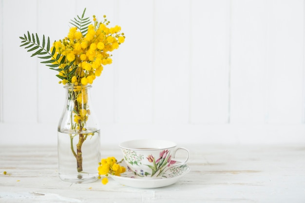 Wooden table with cup of tea and vase with flowers