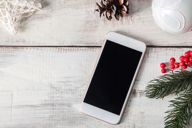 Free photo wooden table with a phone and christmas decorations.