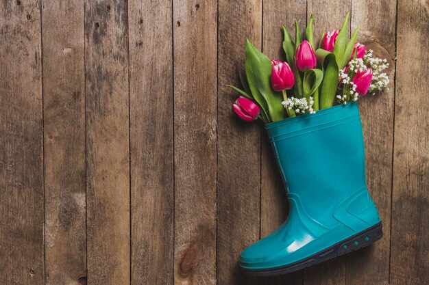 Wooden table with plastic boot and decorative flowers