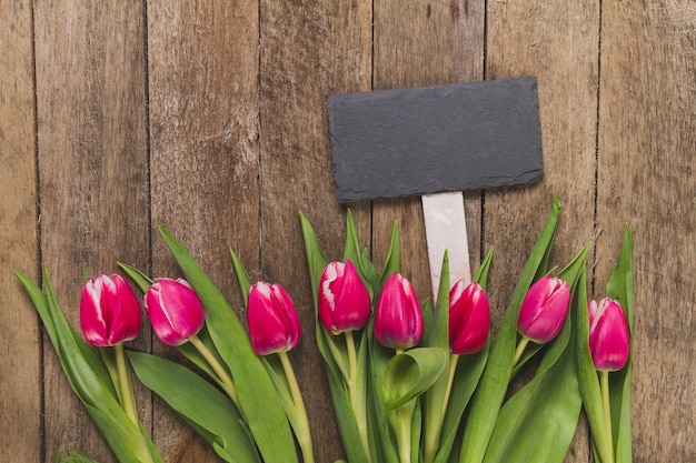 Wooden table with sign and tulips in row