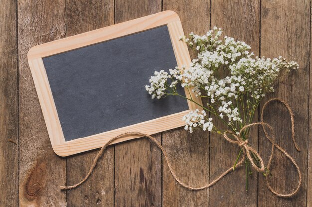 Wooden table with small blackboard and floral decoration