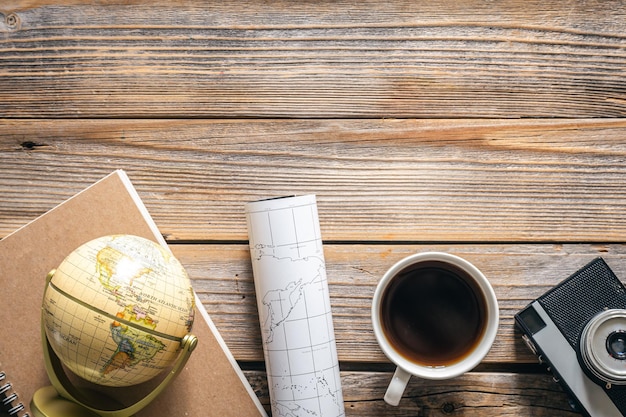 Free photo wooden travel background with globe map camera and coffee top view