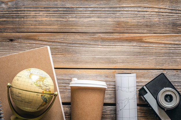 Wooden travel background with globe map camera and coffee top view