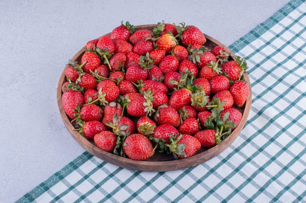 Wooden tray full of strawberries on marble background. High quality photo