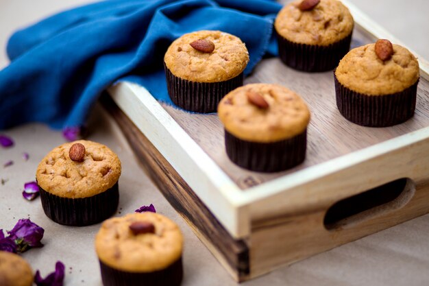 A wooden tray with basic muffins with almond on top
