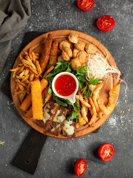 Wooden tray with potatoes, cheese sticks and fried croutons