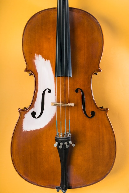 Wooden violin with string on yellow background