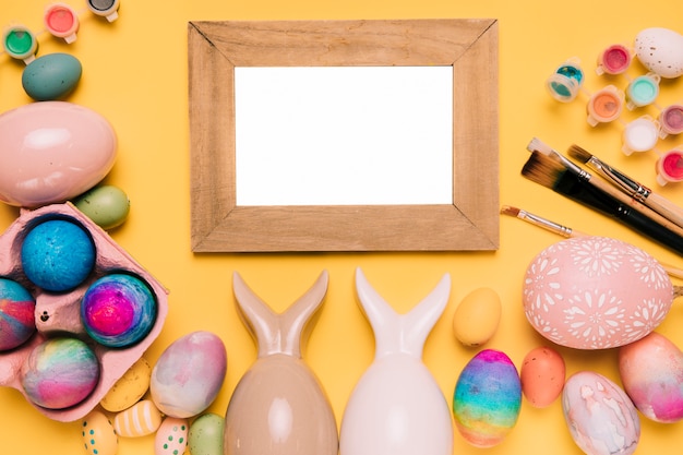 Free photo wooden white frame with colorful easter eggs on yellow background