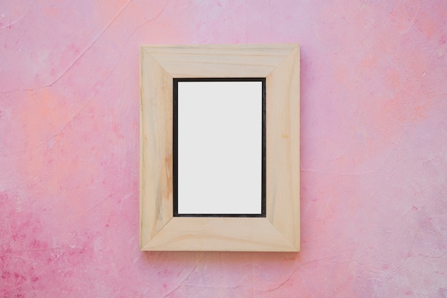 Wooden white picture frame on painted pink wall