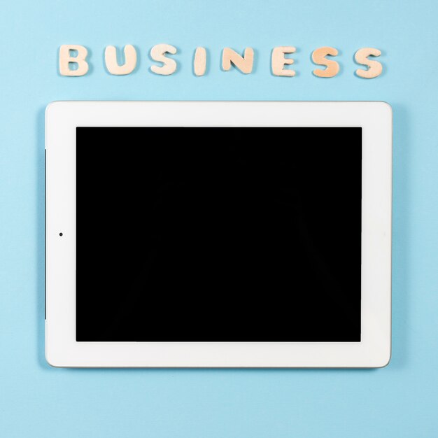 青い背景にデジタルタブレットの上に木製の単語ビジネス