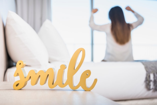 Free photo wooden yellow smile text with her woman walking up on bed