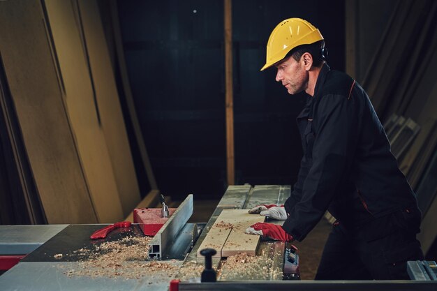 The woodworker is leaning at the wooden table.