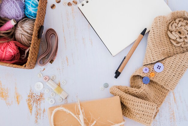 Wool balls in basket; measuring tape; button and crochet on wooden desk