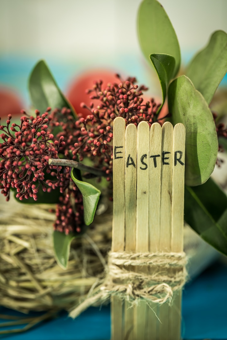 Free Photo the word easter in the conceptual block text on wooden sticks, beautiful festive eggs with greens