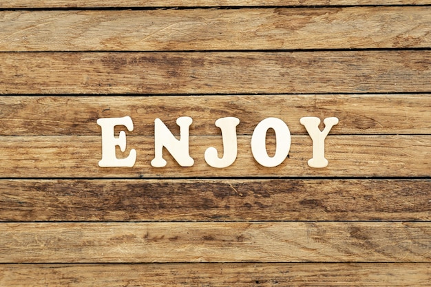 Free photo the word enjoy composed of wooden letters on a wooden background