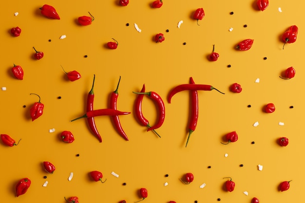 Free photo word hot made of red spicy mexican chili pepper of long shape isolated over yellow background. chili spelling word. vegetables, spices and vegetarian diet concept. agriculture and fresh food.