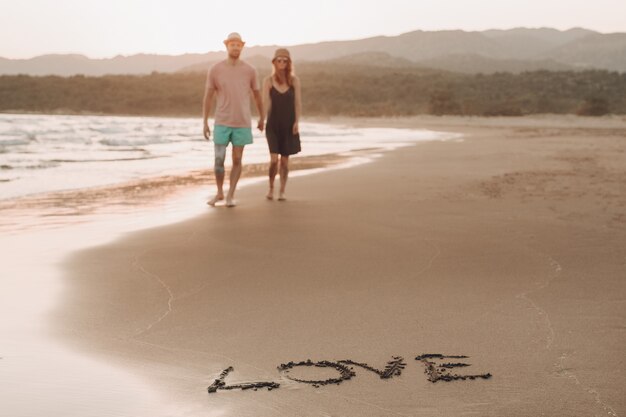 砂の海岸の単語愛と背景散歩に恋人カップをぼやけ