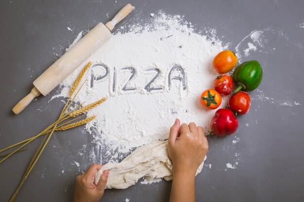 Word pizza written on flour with ingredients