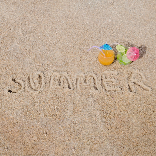 Free photo word on sand with cocktails