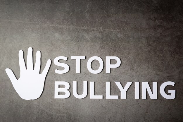 Word "stop bullying" with hand sign on dark wall