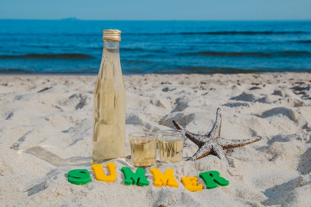 Word 'Summer' and bottle on beach