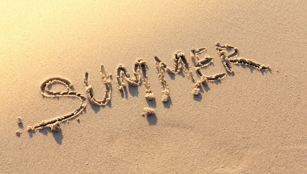 Word summer written on sandy beach