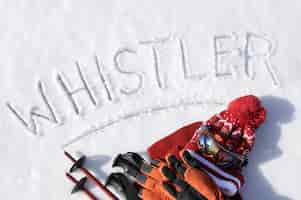 Free photo the word whistler written in snow with ski poles, goggles and hats