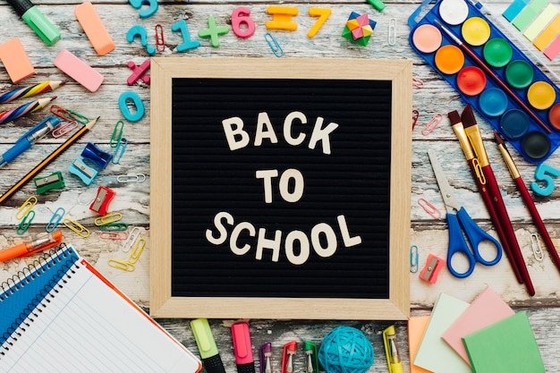 Foto gratuita le parole back to school, scritto in gesso sulla scrivania della scuola con il primo piano di materiale scolastico.