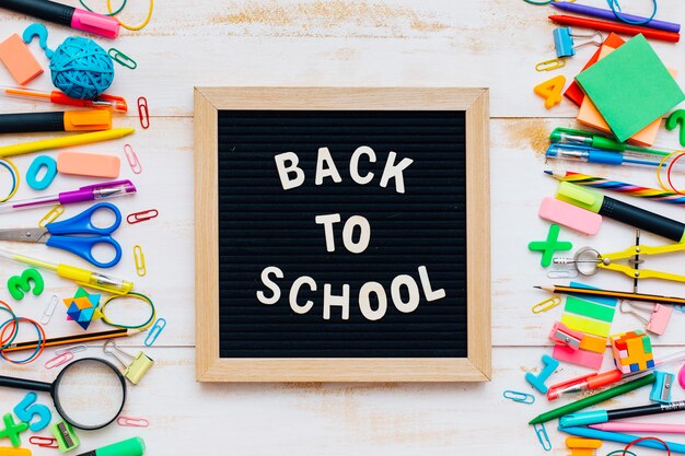 The words Back to School written in chalk on school desk with school supplies close-up