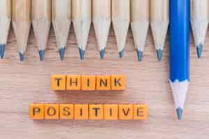 Free photo words think positive on wooden table with group of pencils.