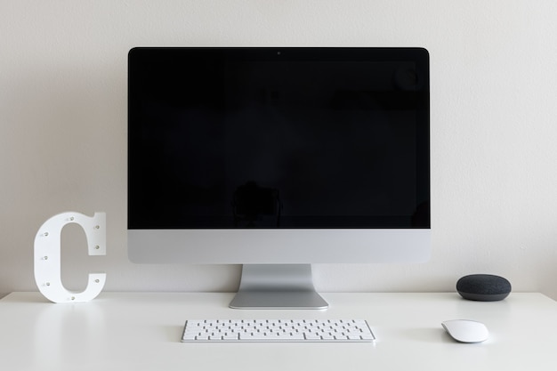 Foto gratuita scrivania con un computer e la lettera c contro un muro bianco