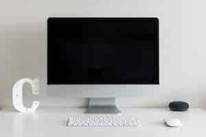 Free photo work desk with a computer and the letter c against a white wall