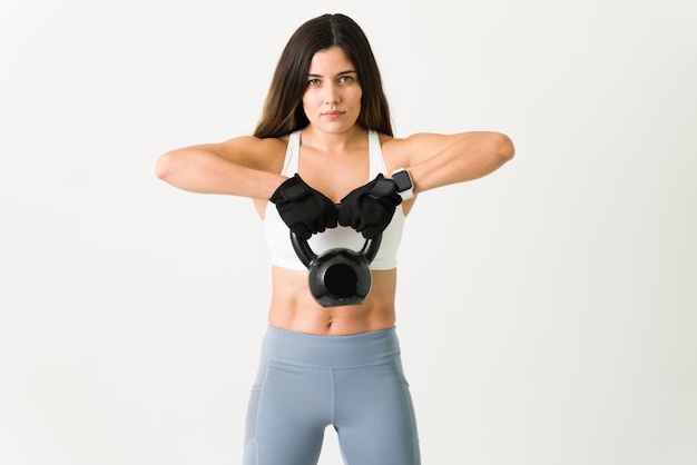 Work hard to have a strong body. Gorgeous young woman working out her biceps and back with a kettlebell weight