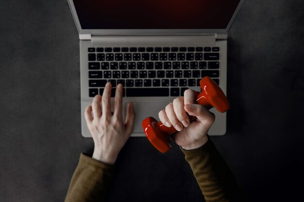 Work life balance concept. young woman holding a dumbbell to exercising hand and arm while working on computer laptop