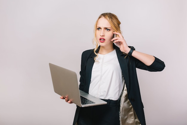 電話で話しているラップトップでフォーマルな服で忙しい若い女性の仕事のオフィスの時間。動揺、驚いた、働いている、職業、秘書、サラリーマン