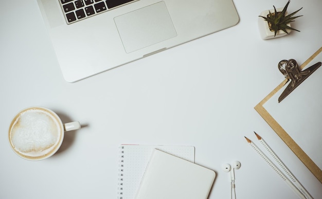 Free photo work space with laptop coffee and stationery on white table top view flat lay