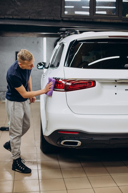 Worker at car detailing cleaning car with microfiber