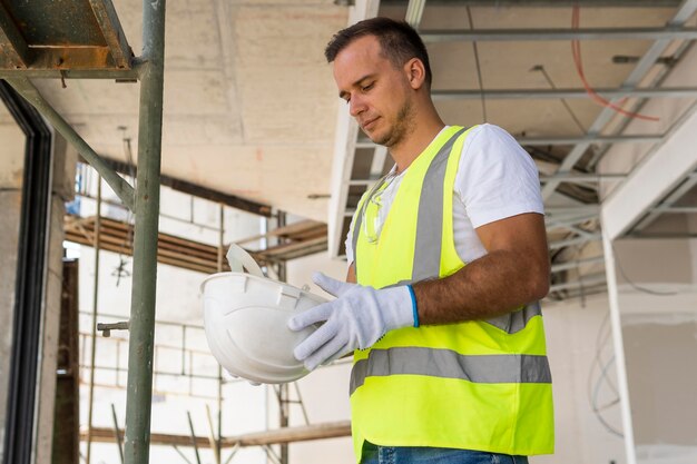 Worker on a construction site holding a helmet